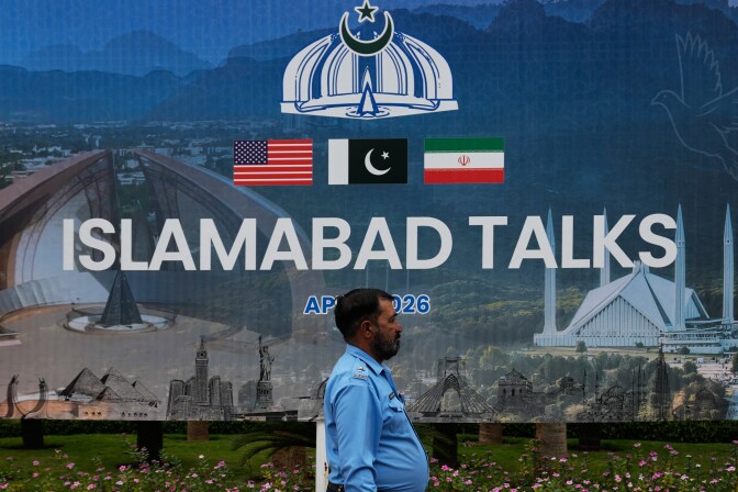 A police officer walks past a billboard that reads "Islamabad Talks."