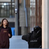 One of the hostages runs towards police from a cafe in the central business district of Sydney on December 15, 2014. Five people ran out of a Sydney cafe where a gunman has taken hostages and displayed an Islamic flag against the window, witnesses and police said December 15, adding that no one has yet been harmed. AFP PHOTO / SAEED KHAN        (Photo credit should read SAEED KHAN/AFP/Getty Images)