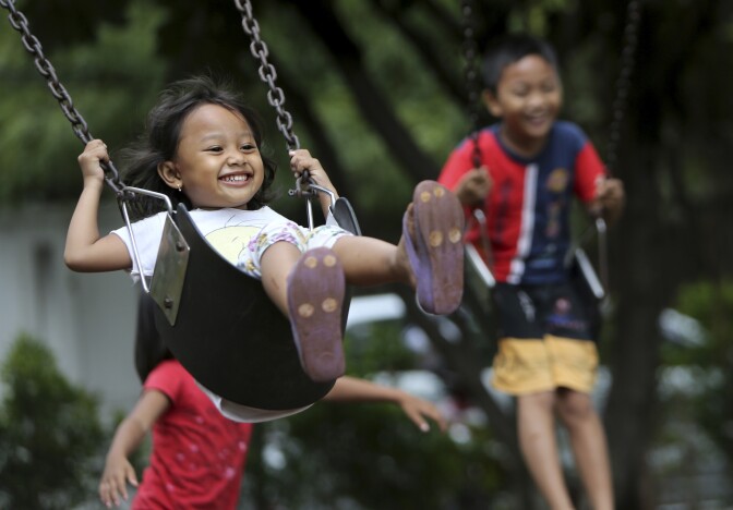 Indonesian children play on swings at a park in Jakarta, Indonesia, Friday. April. 4. 2014.