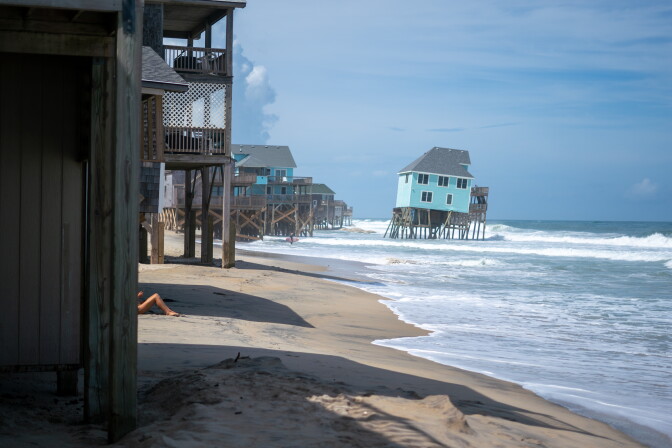 Houses, one of them in water, at a beach.