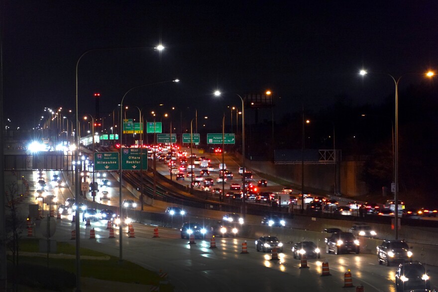 A busy freeway at night with bright headlights driving towards the camera and a line of red brake lights driving away.