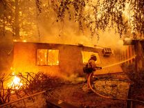 Firefighters battle flames at a burning apartment complex in Paradise, California in November. State fire officials say power lines coming into contact with trees have sparked multiple Northern California wildfires in recent years. PG&E submitted its "wildfire mitigation plan" Wednesday, which lets it cut off power to any of its 5.4 million customers during extremely dry and windy weather.