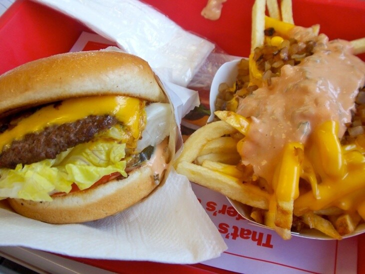 An In-N-Out cheeseburger sits next to a tray of French fries served "Animal Style," that is, smothered in cheese, grilled onions and In-N-Out's beloved take on Thousand Island dressing.