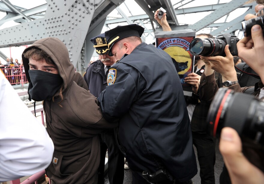 A New York City Police Department officer arrests a mask-wearing Occupy Wall Street protester on the Williamsburg Bridge during a march to Manhattan as the movement joins with activists groups for May Day.