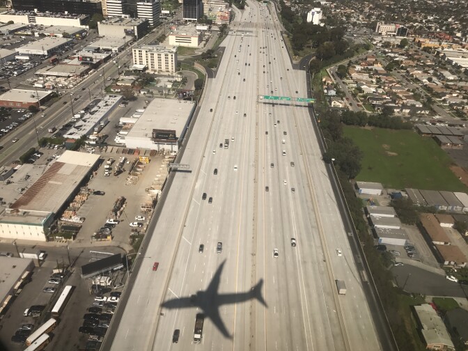 File: The shadow of an airplane is displayed on Highway 405 seconds before landing at Los Angeles (LAX) international airport on Feb. 22, 2017. 