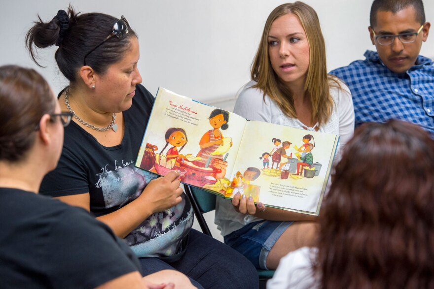 Parent Alicia Ramos, left, works on how to read to her child as parents Lindsey and Rafael Chavez look on during the innovative "Come Read With Me" USC Program that helps develop literacy for deaf and hard of hearing children from bilingual families, July 21, 2016. (USC Photo/Gus Ruelas)