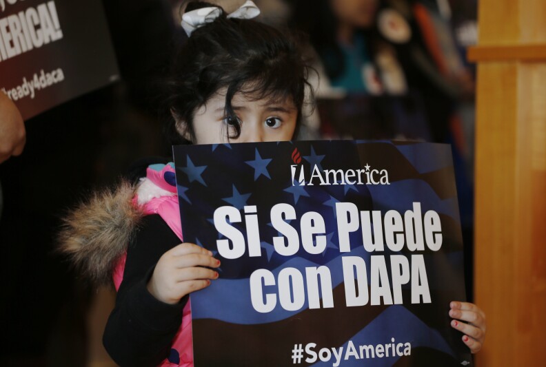 Three-year-old Genesis Moreno Betancurth, of Denver, holds a placard during a news conference in the Denver Public Library, Tuesday, Feb. 17, 2015, in Denver. The White House promised an appeal Tuesday after a federal judge in Texas temporarily blocked President Barack Obama's executive action on immigration and gave a coalition of 26 states time to pursue a lawsuit aiming to permanently stop the orders. (AP Photo/David Zalubowski)
