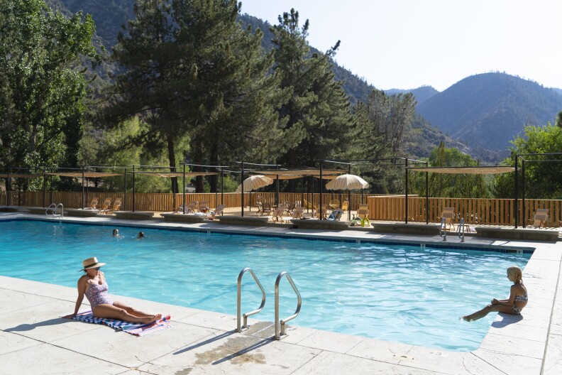 a woman and a child sit next to a large pool