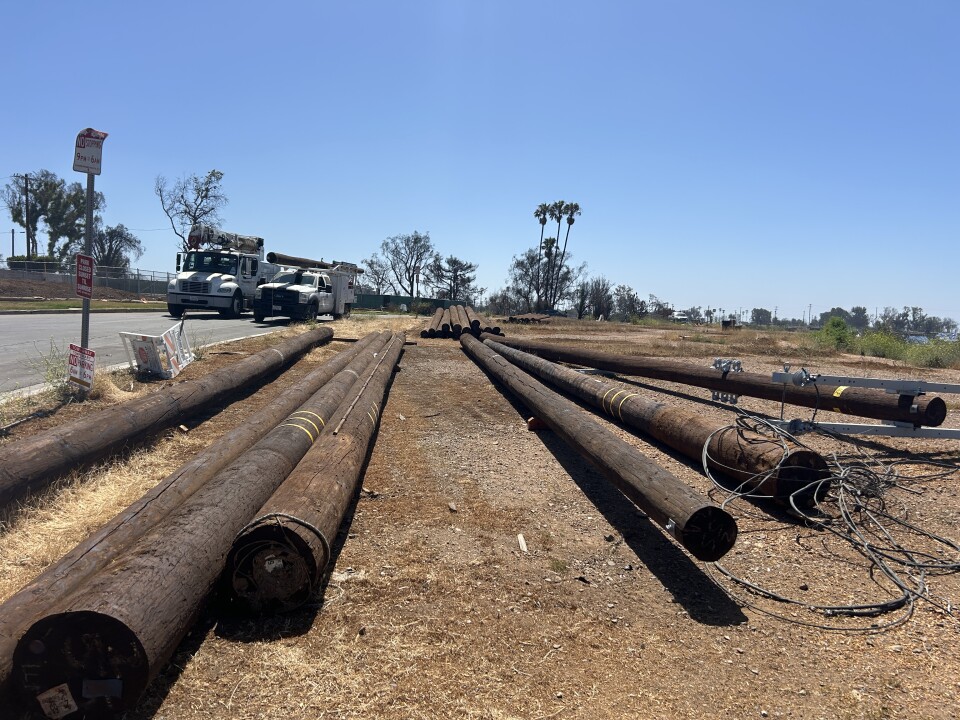 Large power poles on a dirt lot. 