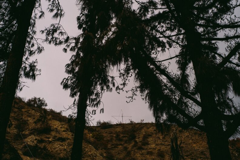 A barely visible sculpture of a star sits above a hillside on a cloudy day