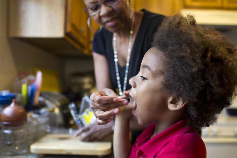 Tonia McMillian, a home-based child care provider, feeds 6-year-old Skylar a blueberry. McMillian is one of many care providers that are organizing to try and improve their pay and work conditions.