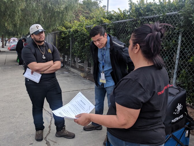 With a bridge home nearby, two outreach workers (left) listen to a woman on the streets of downtown LA, alerting her to a clean-up and inspection of those living on the sidewalks nearby