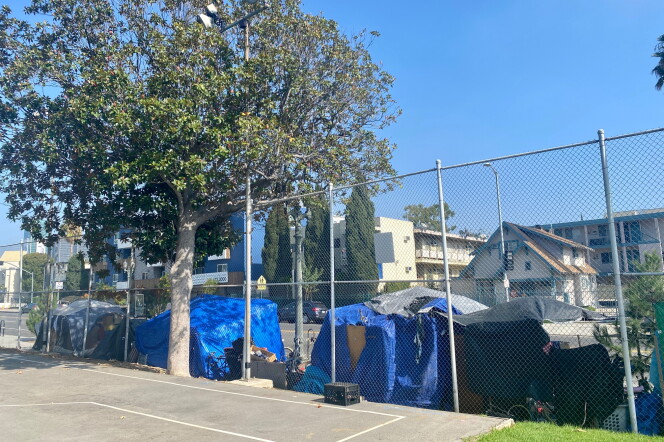 An encampment at the Hollywood Recreation Center are lining the street. the photo is taken from inside the park and the tents are shown on the other side of the fence with apartment buildings across the street. 