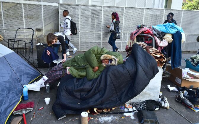 Homeless woman Caroline Francis places a platter of food for her neighbor on the street near the Los Angeles Mission on December 22, 2017.