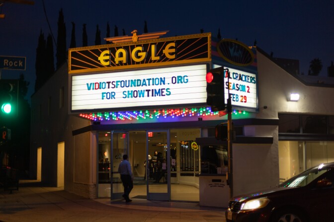 A movie theater that reads "Eagle" in yellow light and a marque that reads "Vidiotsfoundation.org for showtimes."