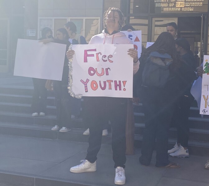 Floyd Lee Hardge stands outside the Board of Supervisors meeting holding a sign that reads "Free Our Youth!" 