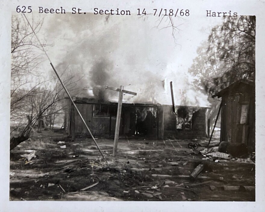 A vintage black and white photo of a small house on fire.