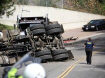 A Los Angeles Coroners official walks by the scene of a wreck Friday March 7, 2014 where a Los Angeles police officer was killed and another critically injured, when their cruiser was struck by a big rig at a Beverly Hills, Calif., intersection.  LAPD Officer Rosario Herrera says the collision occurred shortly before 8 a.m. Friday at Robert Lane and Loma Vista Drive, in a residential area of the city. (AP Photo/Nick Ut )