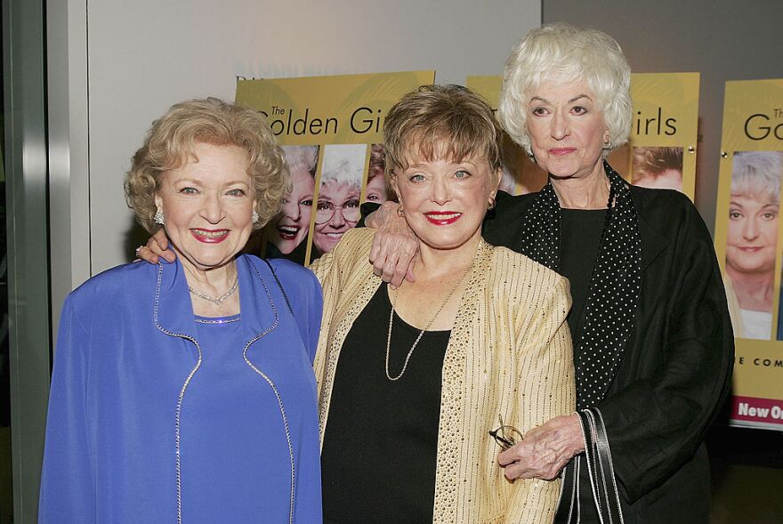 The three main cast characters of the show "The Golden Girls" are pictured in vibrant, darker colored attire for a DVD release party.