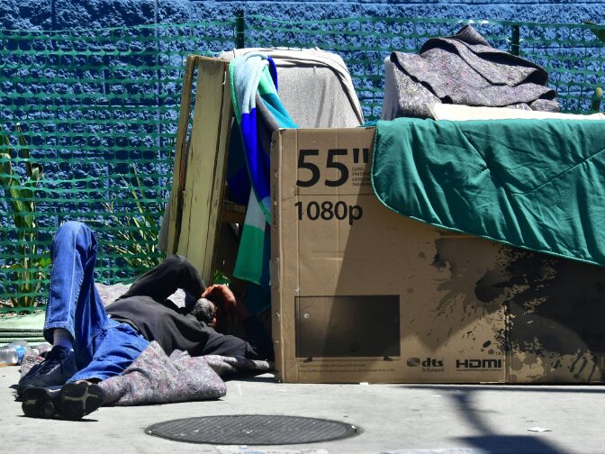 A homeless man sleeps beside his makeshift temporary shelter on a street in downtown Los Angeles, California on June 25, 2018, as a United Nations report on poverty and inequality says 185 million Americans are living in extreme poverty.
