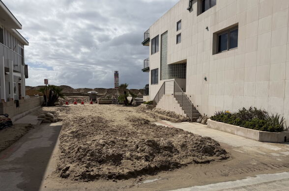 Sand remains on a residential street near the beach after flooding.