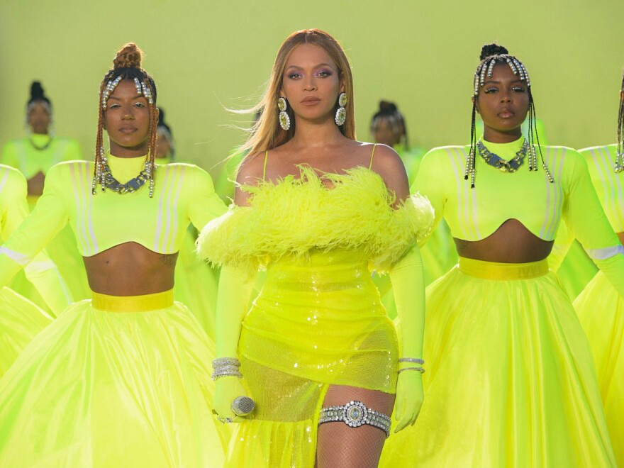 Beyoncé is shown in all neon green with two dancers flanking her on either side. She is performing during the Oscars on March 27.