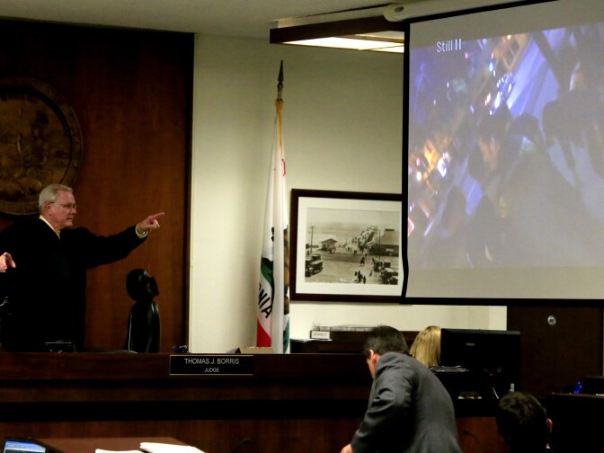 Orange County Superior Court Judge Thomas J. Borris stands up to tell the court to dim the lights while a video of the Kim Pham beating is being played at the West Justice Center on February 10, 2014 in Westminster, California. The video was one of several pieces of evidence presented during the first day of a preliminary hearing for Candace Marie Brito and Vanesa Zavala who are facing charges in the beating death of Kim Pham in front of a Santa Ana nightclub.