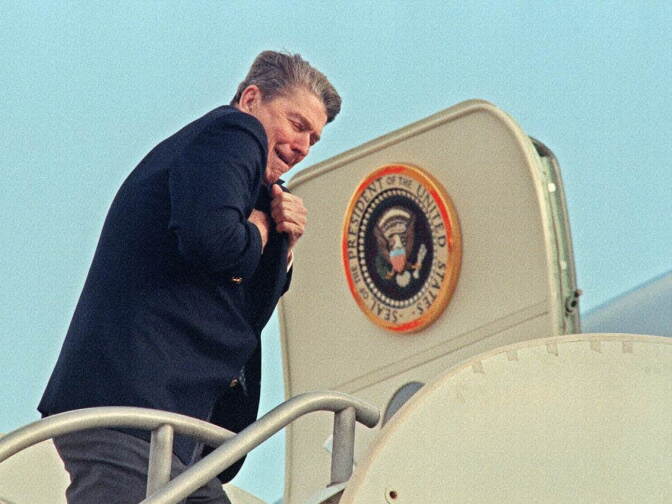 Then US president Ronald Reagan protecting himself from chilling winds at Los Angeles International Airport on December 29, 1987 as he boards Air Force One for a flight to Palm Springs, CA, where the first family spent New Year's Eve.