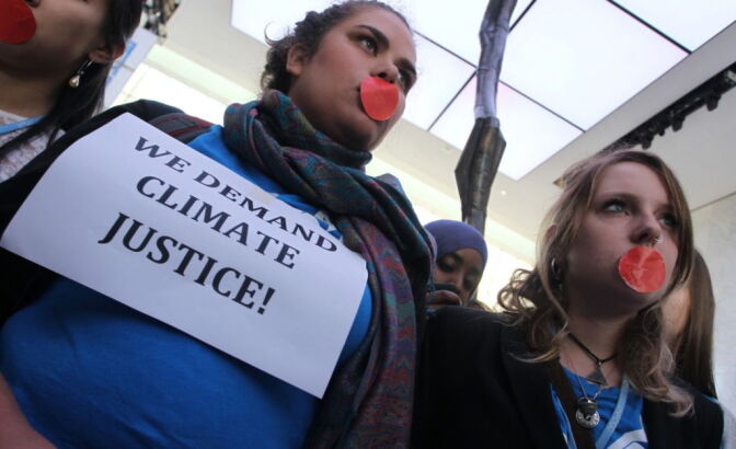 Local and international activists march inside a conference center to demand urgent action to address climate change at the UN climate talks in Doha, on December 7, 2012. UN climate negotiators locked horns on the final day of talks in Doha to halt the march of global warming, deeply divided on extending the greenhouse gas-curbing Kyoto Protocol and funding for poor countries.