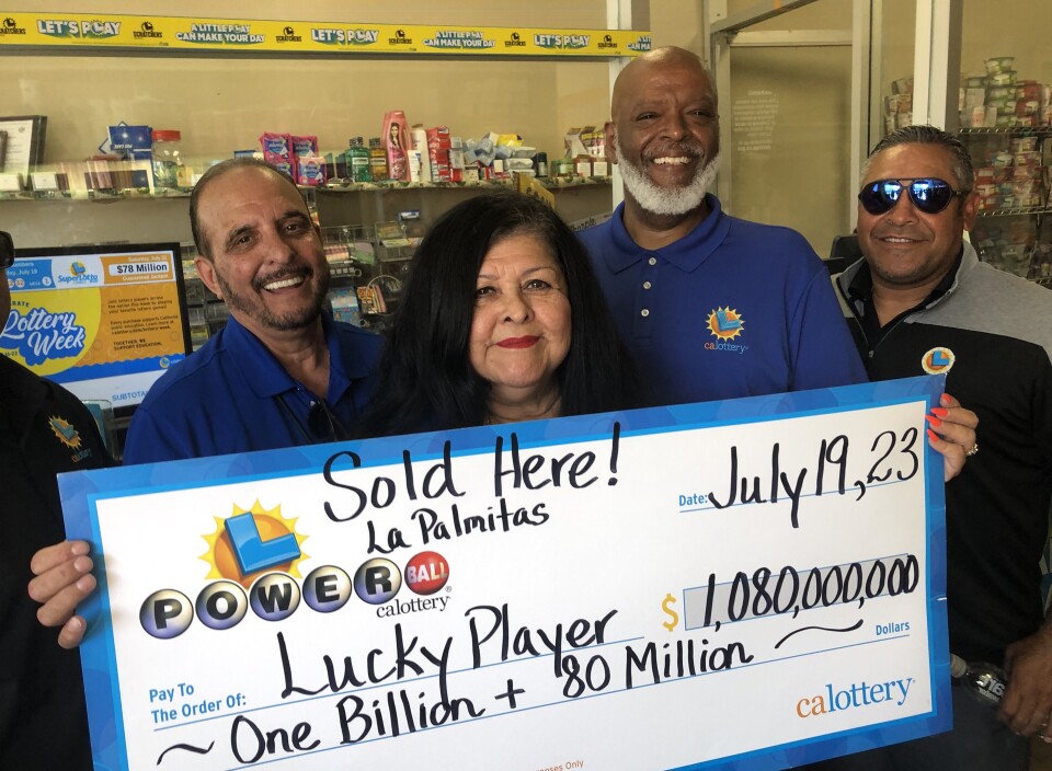 Three people inside a convenience store hold up a large, replica check for $1.08 billion.