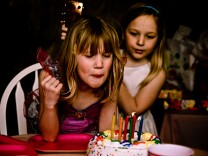 A girl blows out birthday candles.
