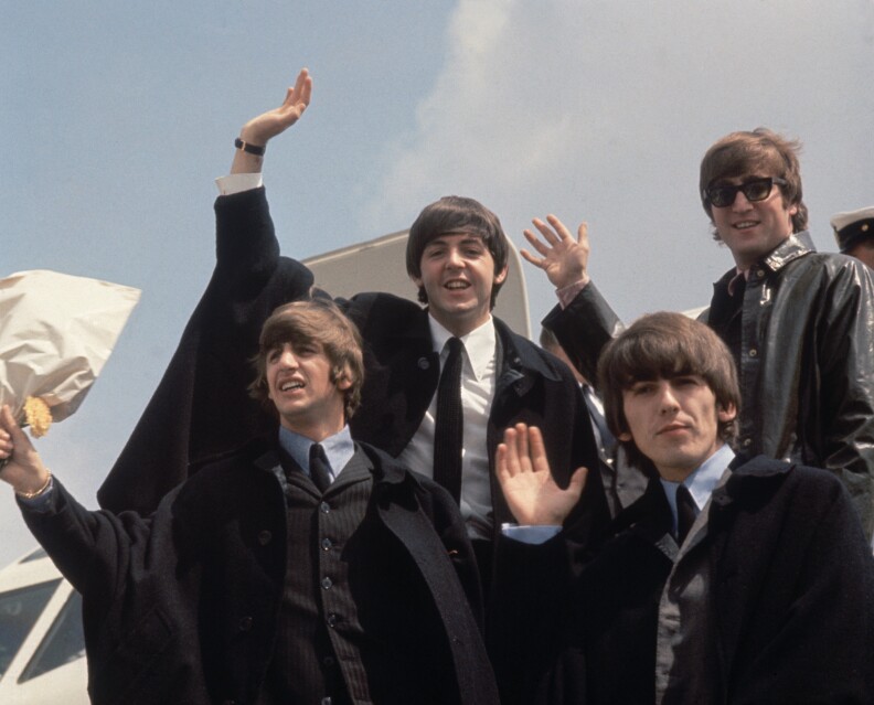 2nd July 1964:  The Beatles (from left to right, John Lennon (1940 - 1980), George Harrison (1943 - 2001), Paul McCartney and Ringo Starr) arrive back at London Airport after their Australian tour. So what do you say--The Beatles or The Rolling Stones?