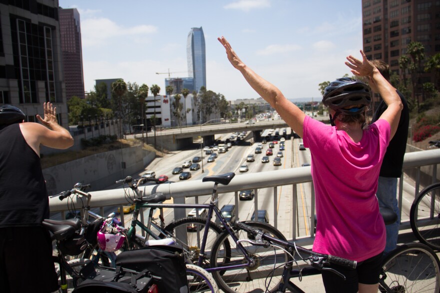 Susan Dalton waves to motorists on the 110 freeway from the Wilshire Boulevard overpass near downtown L.A. during CicLAvia on June 23, 2013.
