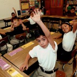 Caption:TYLER,TX - SEPTEMBER 11: Monolingual Hispanic students raise their hands to answer a question during a class taught in Spanish at Birdwell Elementary School September 11, 2003 in Tyler, Texas. The first grade students spend half their school day learning reading, writing, and arithmetic in Spanish and the other half learning them in English. Birdwell, a school of 600 students, 60 percent of them Hispanic with a significant portion of them Spanish speakers, requires a dual-language curriculum for it?s kindergarten and first graders. (Photo by Mario Villafuerte/Getty Images)

