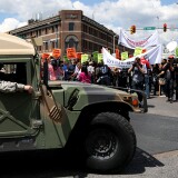 BALTIMORE, MD - MAY 02: A National Guard truck drives by protesters at North Ave., and Pennsylvania Ave., a day after Baltimore authorities released a report on the death of Freddie Gray on May 2, 2015 in Baltimore, Maryland. Marilyn Mosby, Baltimore City state's attorney, ruled the death of Freddie Gray a homicide and that criminal charges will be filed on six Baltimore City Police officers. Gray, 25, was arrested for possessing a switch blade knife April 12 outside the Gilmor Houses housing project on Baltimore's west side. According to his attorney, Gray died a week later in the hospital from a severe spinal cord injury he received while in police custody. (Photo by Patrick Smith/Getty Images)