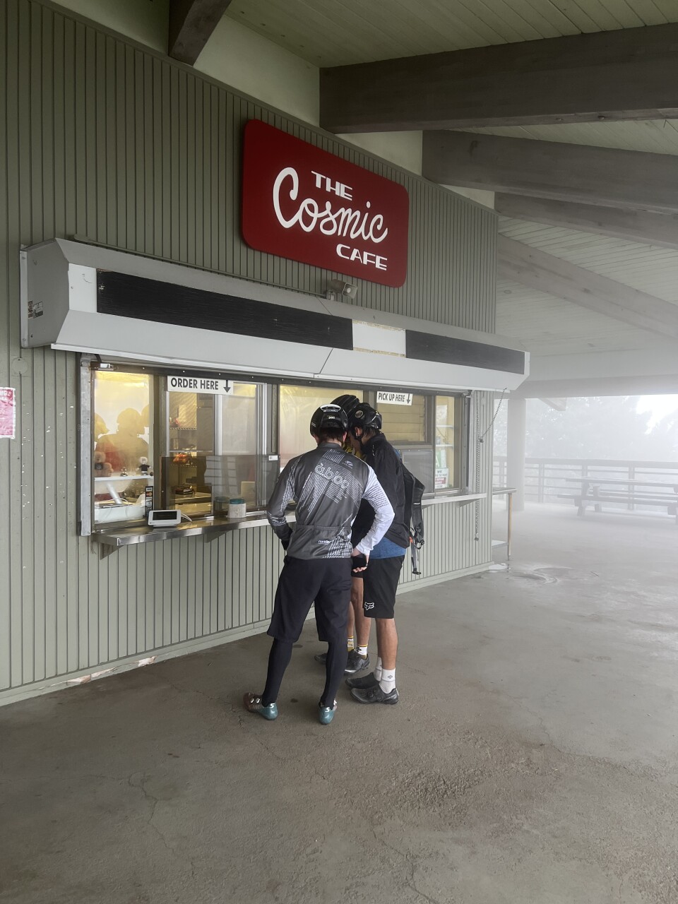 Two people standing in front of food service window on a foggy day.