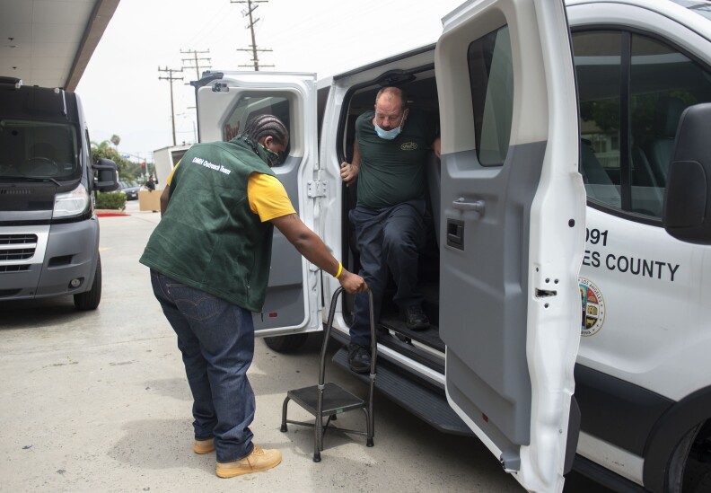 Mark Fowler, of DMH’s HOME Team, helps Chris Herrin step down from the county van upon arrival at the hotel participating in Project Roomkey, the county’s temporary housing program.