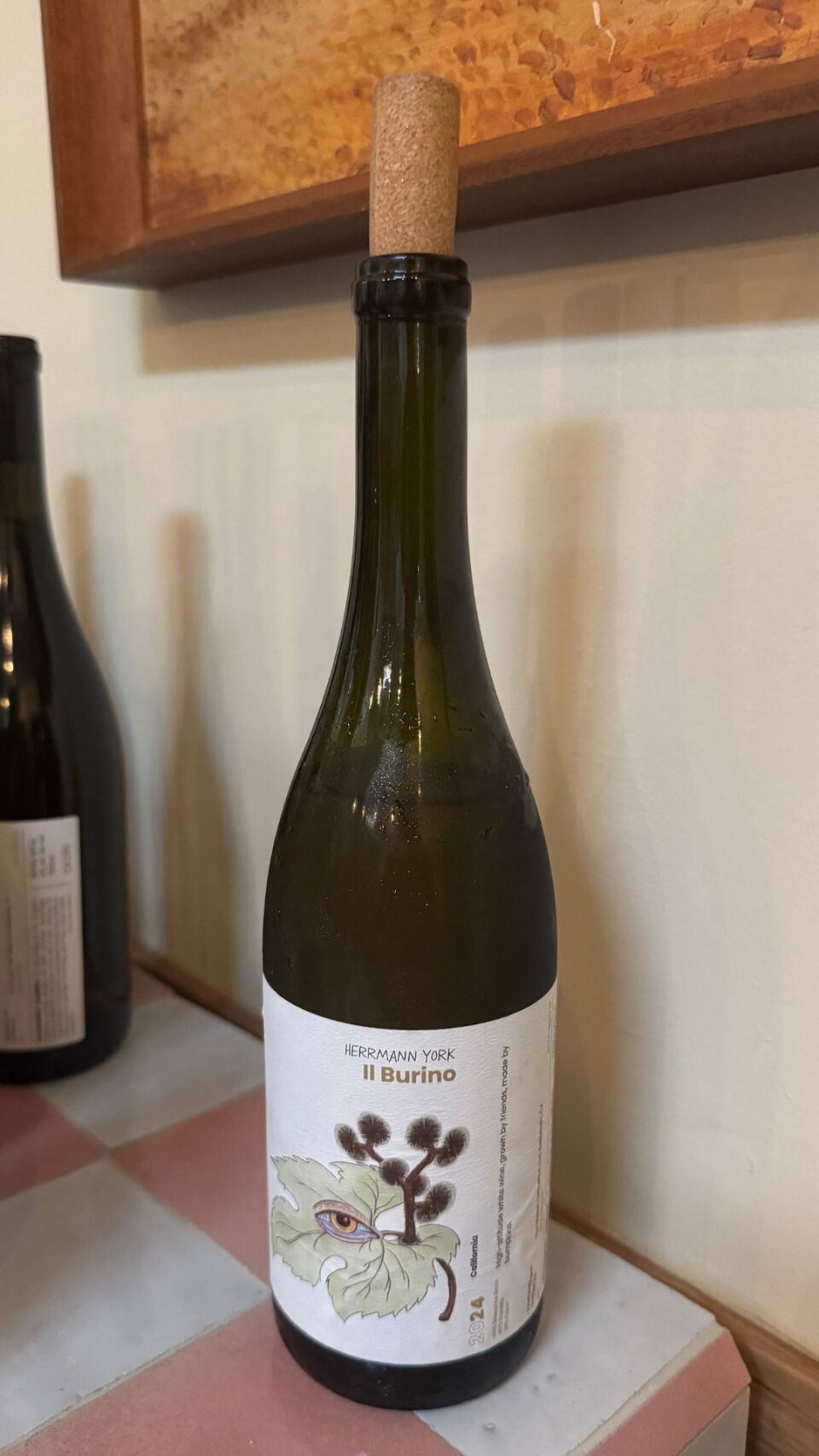 A bottle of wine with a label that has an eyeball and some plants on it. 