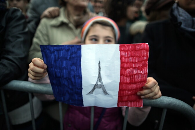 A child holds-up a hand drawn French flag as people gather on November 14, 2015 in Turin, a day after deadly attacks in Paris. At least 128 people were killed in the Paris attacks on the evening of November 13, with 180 people injured, 80 of them seriously, police sources told. 