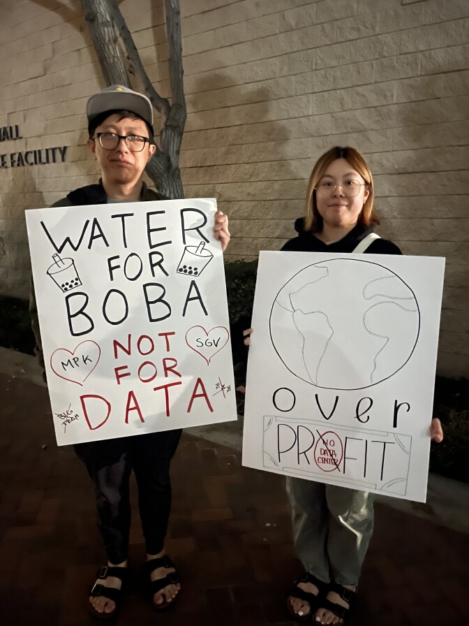 An Asian American man carries a sign that reads "Water for Boba Not for Data" and an Asian American woman holds a sign with the picture of an earth over the words "over profit."