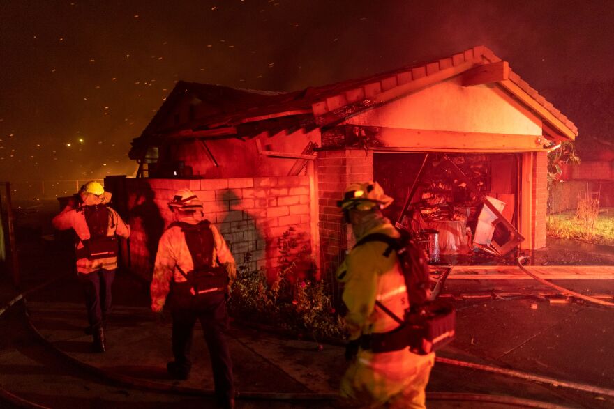 Firefighters work to save homes from the Saddleridge Fire in the Porter Ranch section of Los Angeles, California, on October 11, 2019.