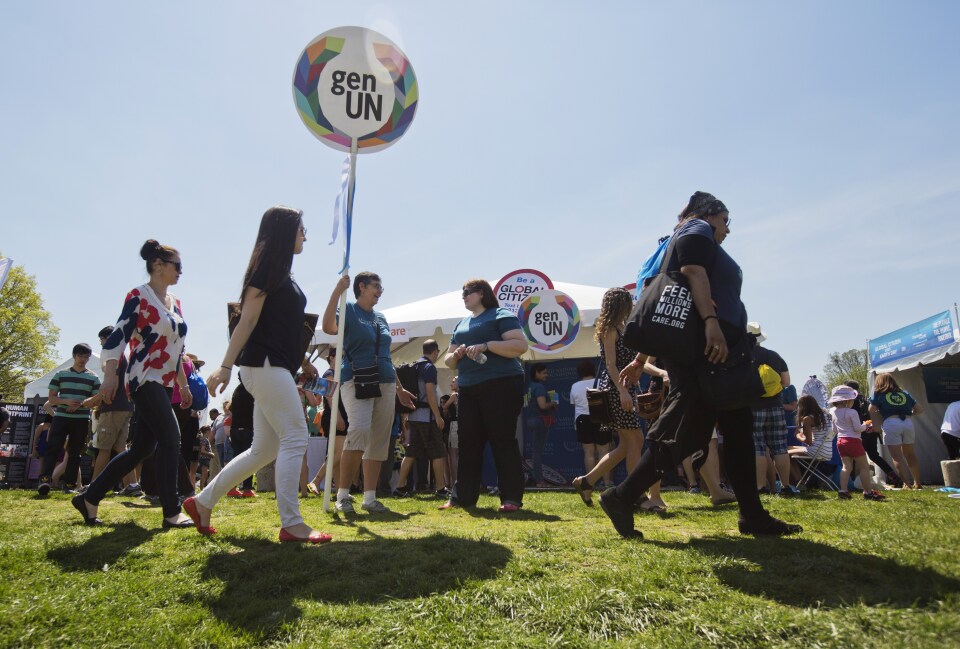 Concert attendees walk past information stands during the 2015 Earth Day concert in Washington, DC on April 18, 2015.