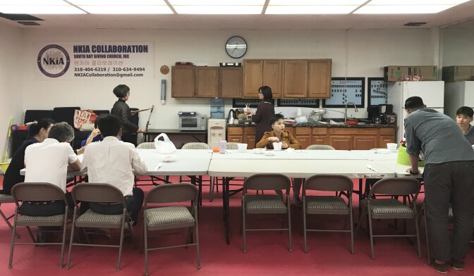 May Joo, center, shares a beef, rice and kimchi lunch after the church service will fellow members.