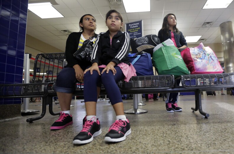 Immigrants from El Salvador and Guatemala who entered the country illegally wait at a bus station after they were released from a family detention center, Tuesday, July 7, 2015, in San Antonio. Women and children are being released from immigrant detention centers faster on bond, with many mothers assigned ankle monitoring bracelets in lieu of paying. (AP Photo/Eric Gay)