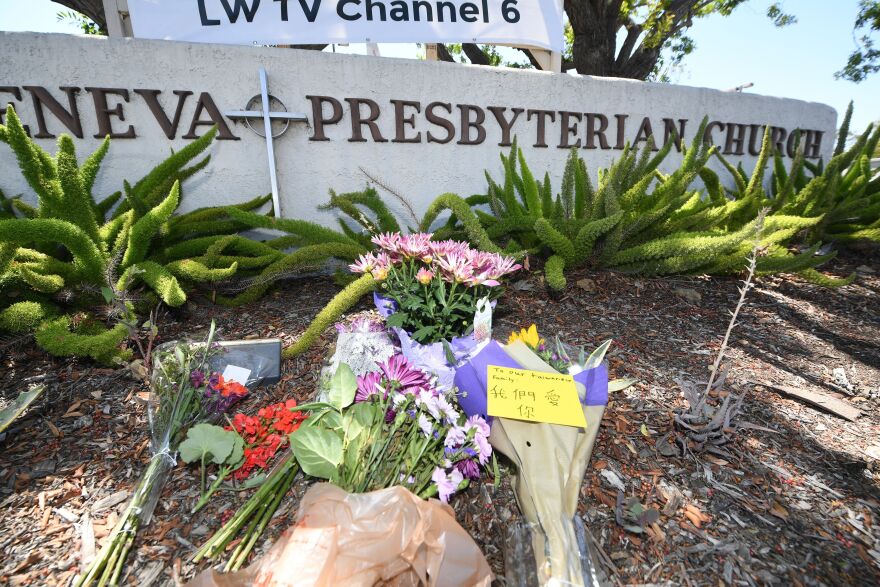 Bouquets of flowers were placed on a small landscaped berm with native plants in front of a low wall that reads Geneva Presbyterian Church (the world Geneva is partially obscured).