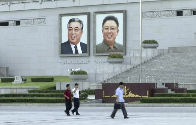 In this image made from video, pedestrians walk beneath portraits of Kim Il Sung, left, and Kim Jong Il, at Kim Il Sung square in Pyongyang, North Korea, Friday, Aug. 11, 2017. Despite tensions and talk of war, life on the streets of the North Korean capital Pyongyang remained calm. (AP Photo)