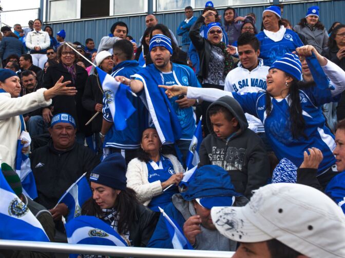 Fans in the crowd at Duarte High School fight over free El Salvador flags passed out at the event.