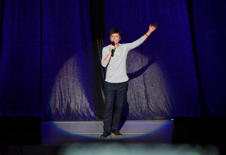 Comedian Tig Notaro stands in the spotlight alone on stage.