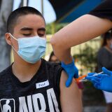 Hector Garnica, 13, receives a first dose of the Pfizer Covid-19 vaccine at a mobile vaccination clinic at the Weingart East Los Angeles YMCA on May 14, 2021 in Los Angeles, California. - The campaign to immunize America's 17 million adolescents aged 12-to-15 kicked off in full force on May 13. The YMCA of Metropolitan Los Angeles is working to overcome vaccine hesitancy and expand access in high risk communities with community vaccine clinics in the area. (Photo by Patrick T. FALLON / AFP) (Photo by PATRICK T. FALLON/AFP via Getty Images)