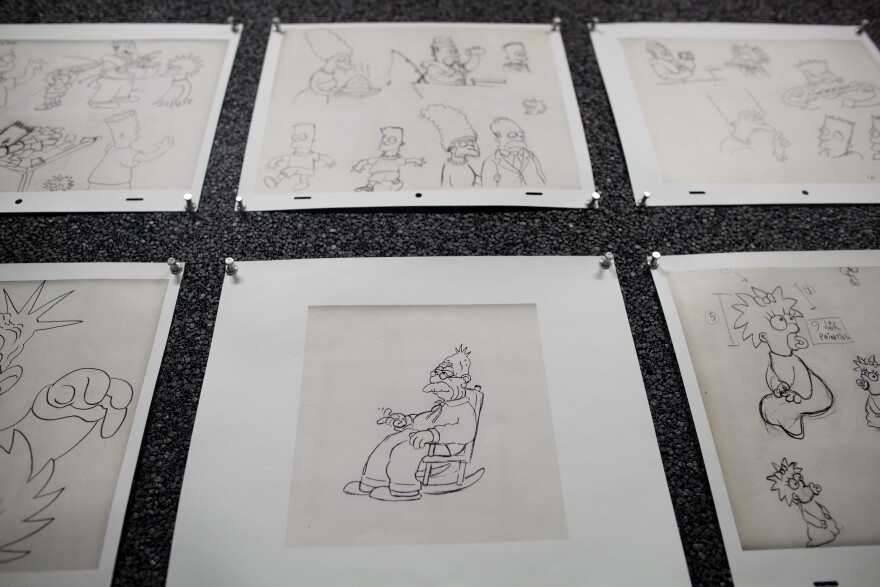 Sketches on the walls of a conference room depict different characters in "The Simpsons."